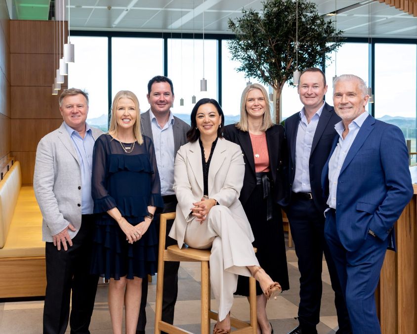 Queensland Airports Limited executive team group photo in office environment.